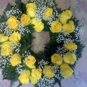 Keltaisista ruusuista ja valkoisista kukista tehty hautaseppele