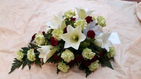 Valkoisist aja tummanpunaisista kukista tehty hautajaiskimppu