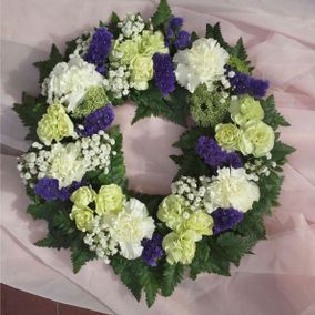 Valkoisista ja violeteista kukista solmittu hautaseppele