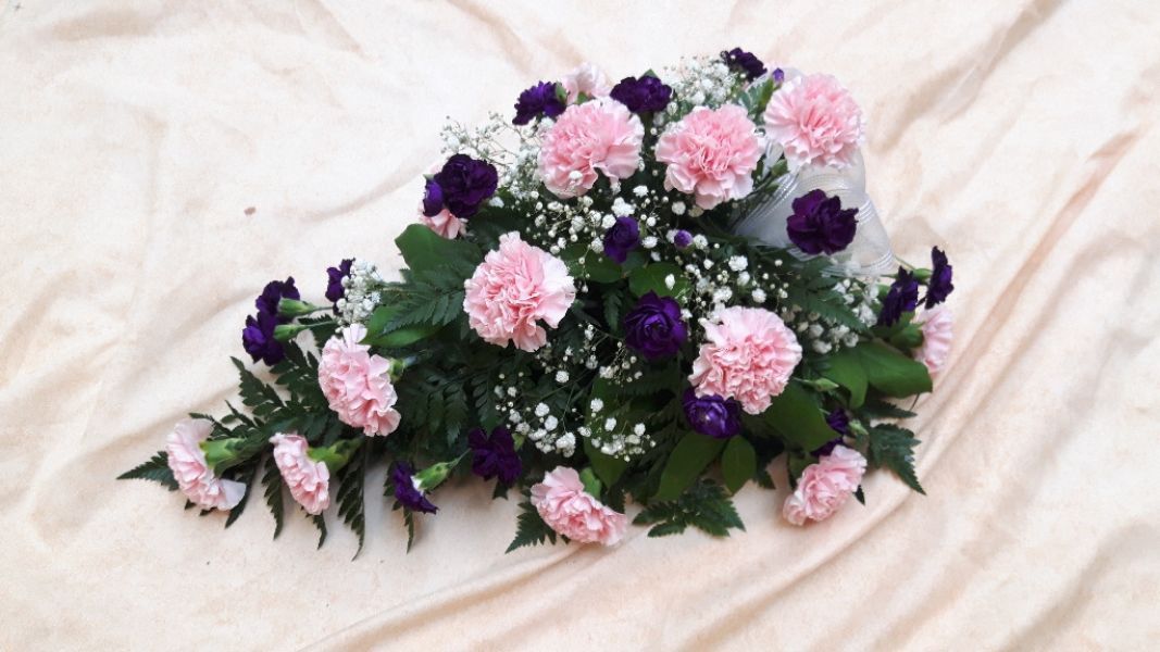 Vaaleanpunaisia ja violetteja kukkia hautajaiskimpussa